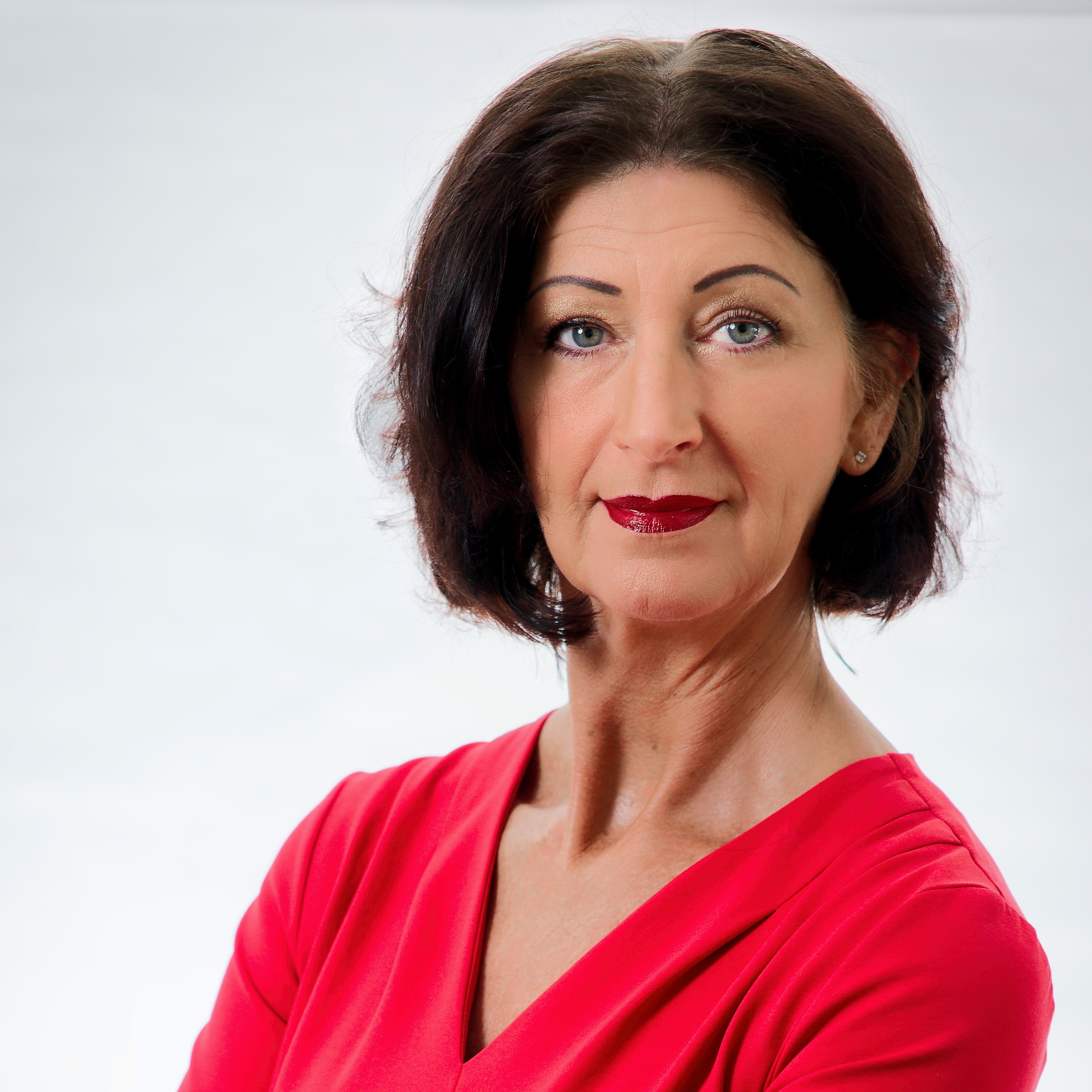 Carmen Lehner, professionelles Portrait im roten Kleid vor hellem Hintergrund.